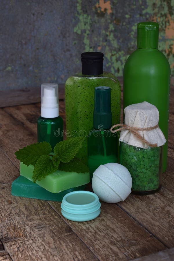 Lime mint composition of beauty threatment products in green colors on brown wooden background: shampoo, soap, bath salt, towel, o