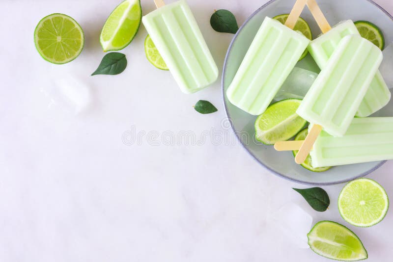 Lime yogurt popsicle corner border, top view against a marble background with copy space. Lime yogurt popsicle corner border, top view against a marble background with copy space