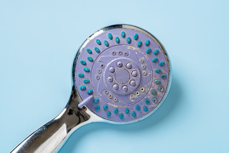 Limescale on an old hand held shower head macro. Handheld shower head with hard water stains over pastel blue background. Bath stock photos