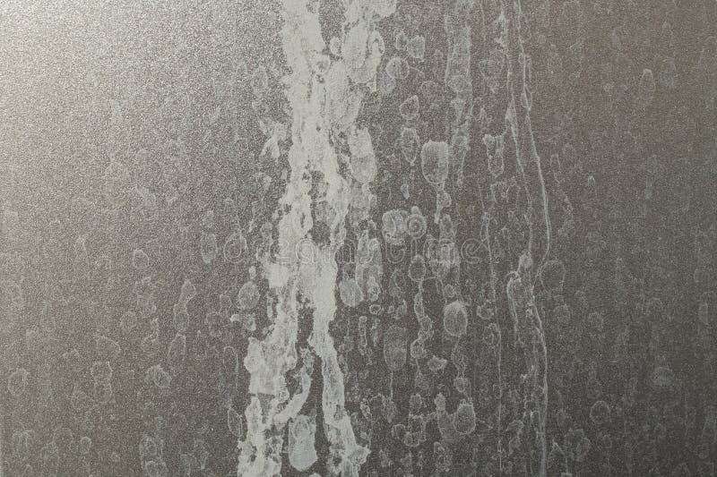 Limescale trails from hard water issue , on metallic gray plastic shower wall, abstract texture royalty free stock photo.