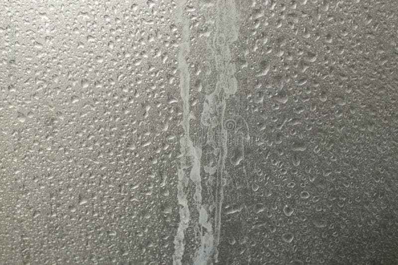 Limescale trails from hard water issue and water drops, on metallic gray plastic shower wall, abstract texture stock photography