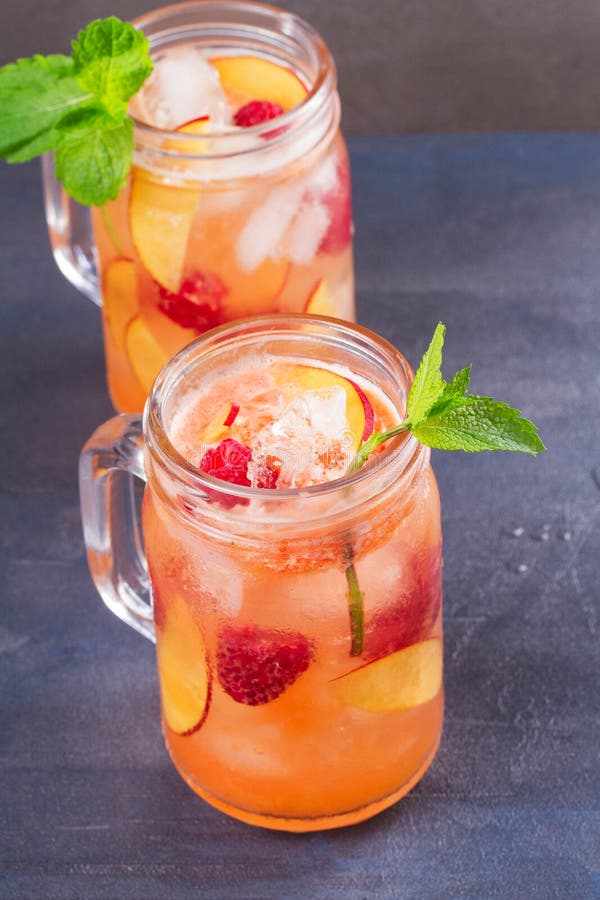 Limonada de la frambuesa del melocotón, adornada con la menta Fruta Berry Cocktail en tarros imagenes de archivo Limonada de la frambuesa del melocotón, adornada con la menta Fruta Berry Cocktail en tarros imagenes de archivo