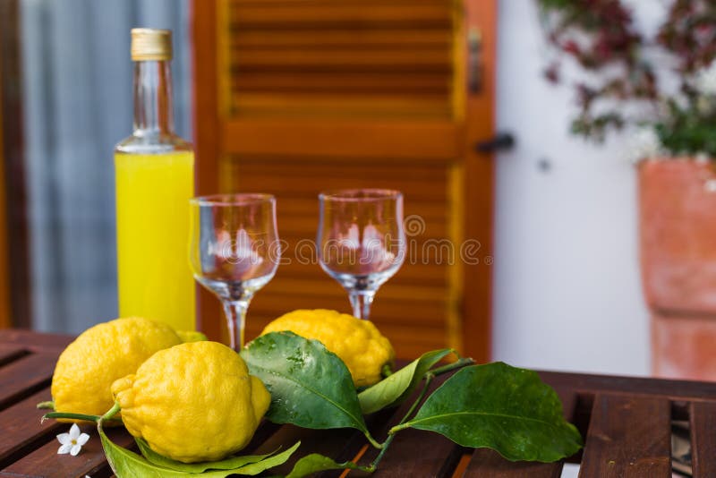 Limonade of limoncello in een glasfles, glazen, citroenen met bladeren op een dienende lijst aangaande het terras royalty-vrije stock fotografie Limonade of limoncello in een glasfles, glazen, citroenen met bladeren op een dienende lijst aangaande het terras royalty-vrije stock fotografie