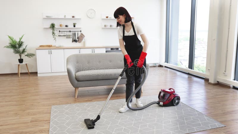 Limpiadora profesional femenina en apron limpia activamente apartamento moderno. almacen de metraje de vídeo