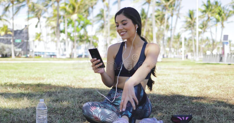 Linda chica con el teléfono al hacer ejercicio en el parque