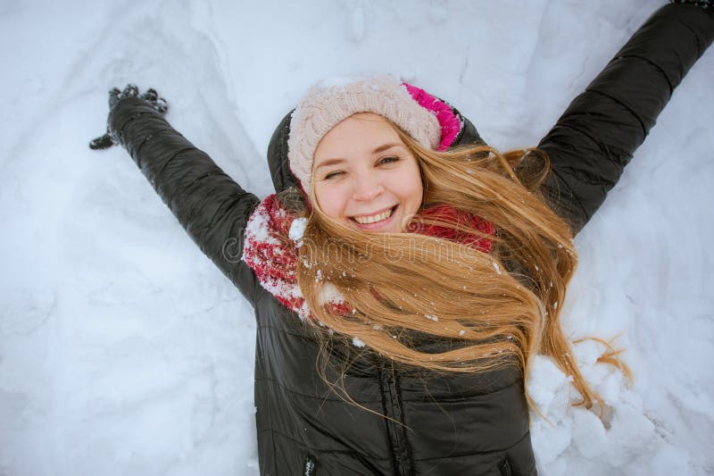 Linda garota feliz está sorrindo e deitada na neve, retrato de close foto de stock Linda garota feliz está sorrindo e deitada na neve, retrato de close foto de stock