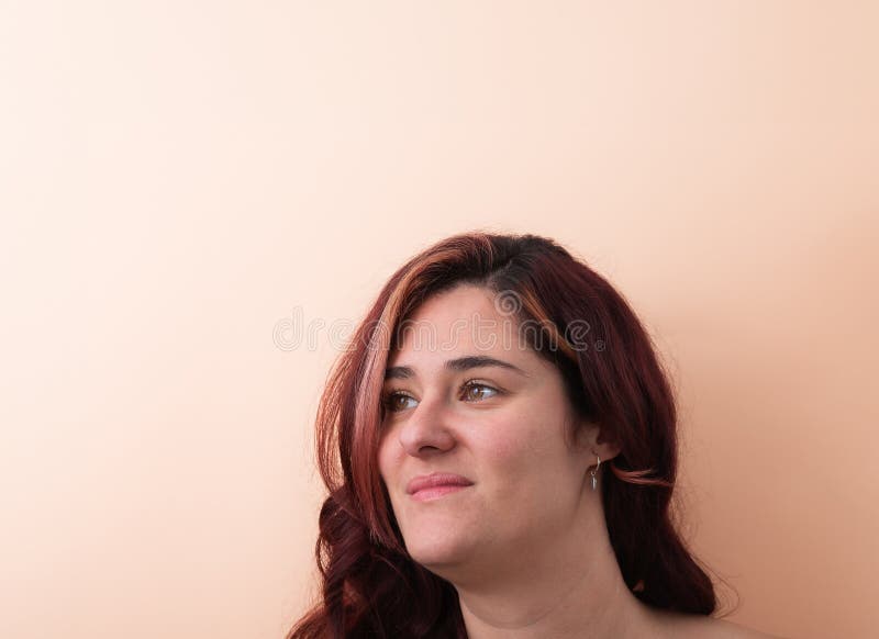 Beautiful 30 years old woman with red hair smiling looking to the side in profile on peach background. Copy space. Natural beauty concept. Beautiful 30 years old woman with red hair smiling looking to the side in profile on peach background. Copy space. Natural beauty concept