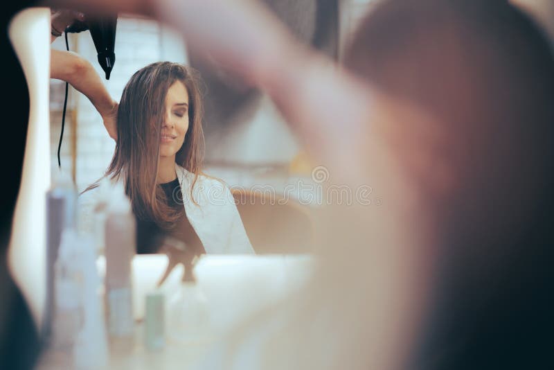 mulher jovem e bonita usando secador de cabelo no salão de