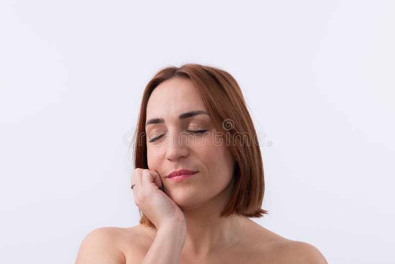 Beautiful 30 years old smiling woman with closed eyes, face leaning on her hand and short red hair, isolated on white background and copy space. Natural beauty concept. Beautiful 30 years old smiling woman with closed eyes, face leaning on her hand and short red hair, isolated on white background and copy space. Natural beauty concept