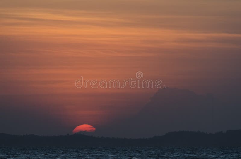 Lindo pôr do sol amarelo e laranja dramático que cai atrás das montanhas imagem de stock