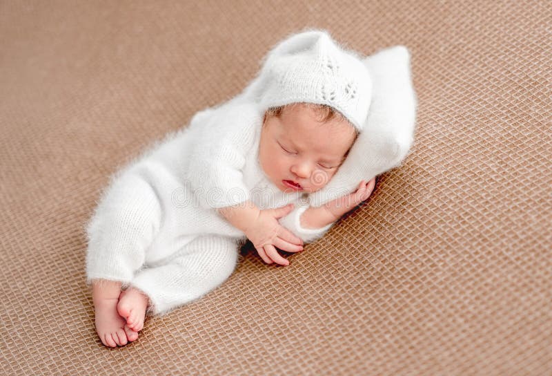 Cute newborn in white suit resting on tiny pillow. Cute newborn in white suit resting on tiny pillow