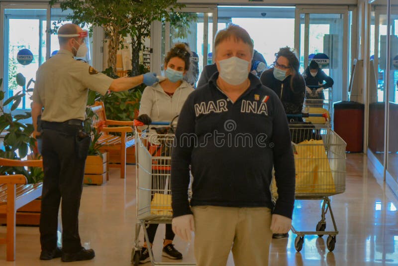 Safety health measures inside an italian shopping mall: security guard checks body temperature to people with COVID-19 masks stock images Safety health measures inside an italian shopping mall: security guard checks body temperature to people with COVID-19 masks stock images