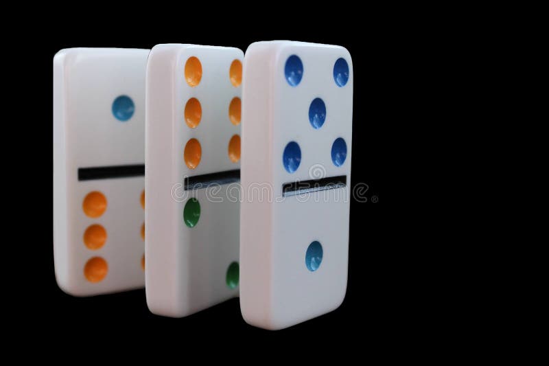 Three standing dominoes isolated on black background metaphor for cause and effect, fate, causality, fallen, chain reaction stock photo