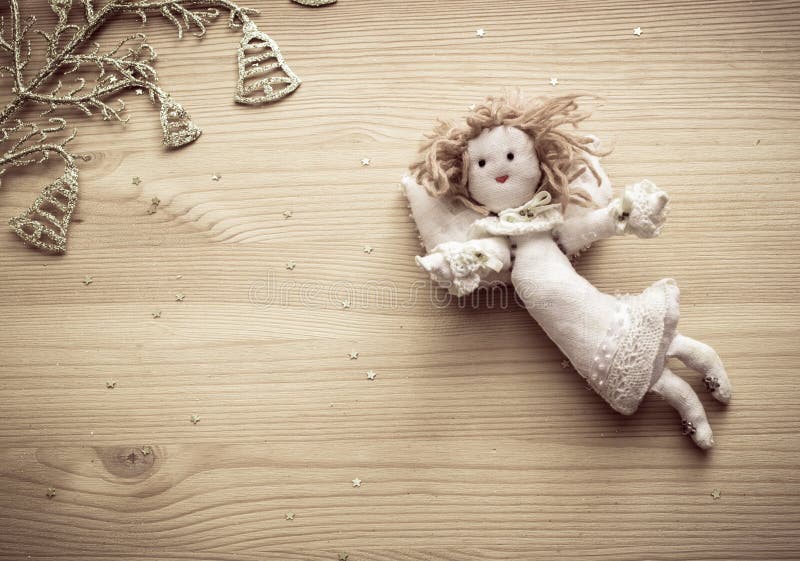 Linen angel, golden bells and stars on wooden background