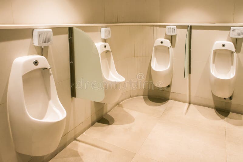 Linha dos mictórios brancos da porcelana em toaletes públicos limpos, claros imagem de stock Linha dos mictórios brancos da porcelana em toaletes públicos limpos, claros imagem de stock