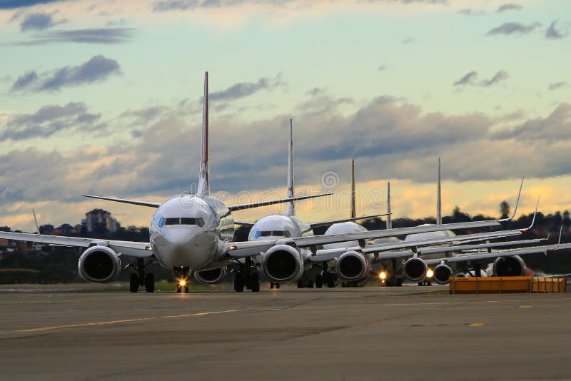 Linje av kommersiella trafikflygplan på landningsbana