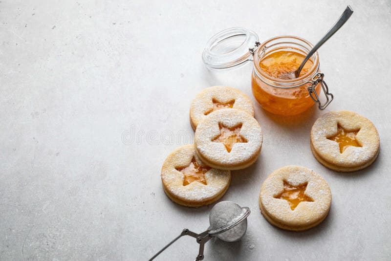 Linzer Christmas or New Year cookies filled with orange jam and dusted with sugar on grey background.