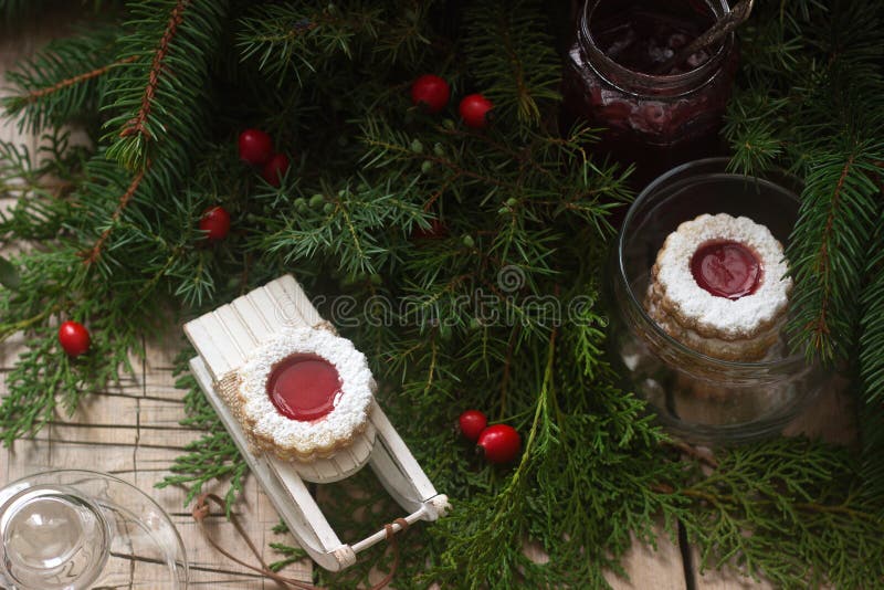 Linzer cookies in a Christmas decoration on a wooden surface.