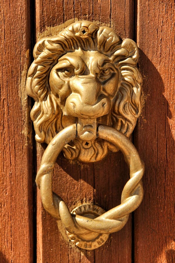 Lion de heurtoir de porte de cru form? sur la porte en bois brune images stock Lion de heurtoir de porte de cru form? sur la porte en bois brune images stock