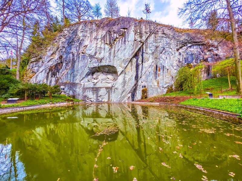 Lion of Lucerne stone monument in the rock with memorial pond in Lucerne, Switzerland