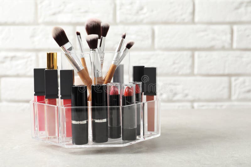 Lipstick Holder with Different Makeup Products on Table Against Brick