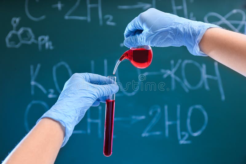 Liquido di versamento dello scienziato nella provetta contro la lavagna Cristalleria di chimica immagine stock libera da diritti Liquido di versamento dello scienziato nella provetta contro la lavagna Cristalleria di chimica immagine stock libera da diritti