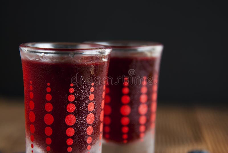 Liquore rosso delle bacche in vetro di colpo isolato su fondo nero e sulla tavola di legno Concetto casalingo della bevanda dell' fotografia stock Liquore rosso delle bacche in vetro di colpo isolato su fondo nero e sulla tavola di legno Concetto casalingo della bevanda dell' fotografia stock