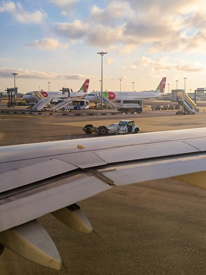 TAP airline planes boarding with bridge at Humberto Delgado airport and luggage transport car at sunrise, Lisbon PORTUGAL. TAP airline planes boarding with bridge at Humberto Delgado airport and luggage transport car at sunrise, Lisbon PORTUGAL