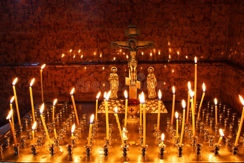 Lit church candles in a gilded candlestick in a temple in the dark. yellow wax lighted candles stand in the church, glow