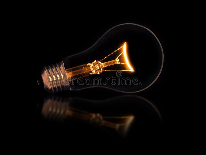 Lit light bulb on black background