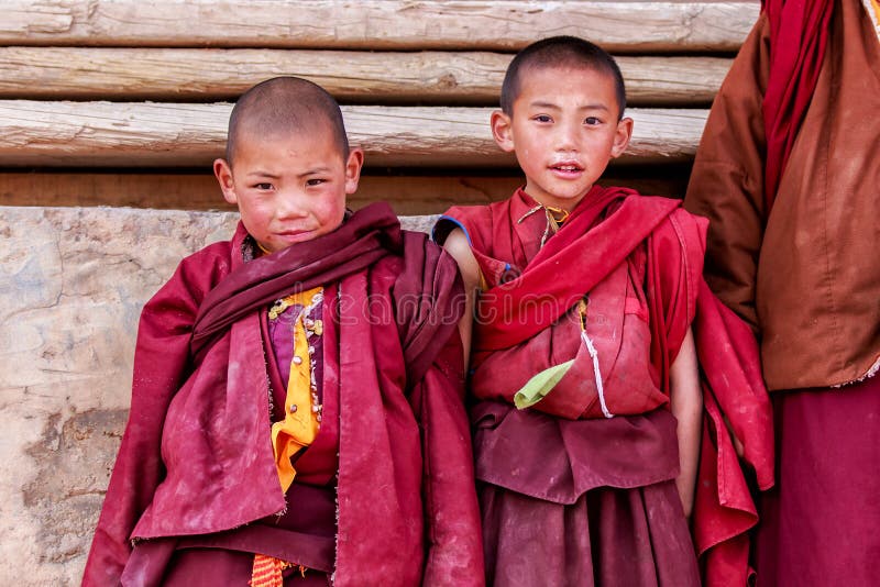 LITANG и GANZI, КИТАЙ - 2-ое мая 2016: Неопознанный усмехаться 2 мальчиков буддийских монахов послушника молит в Boudhanath m стоковая фотография LITANG и GANZI, КИТАЙ - 2-ое мая 2016: Неопознанный усмехаться 2 мальчиков буддийских монахов послушника молит в Boudhanath m стоковая фотография