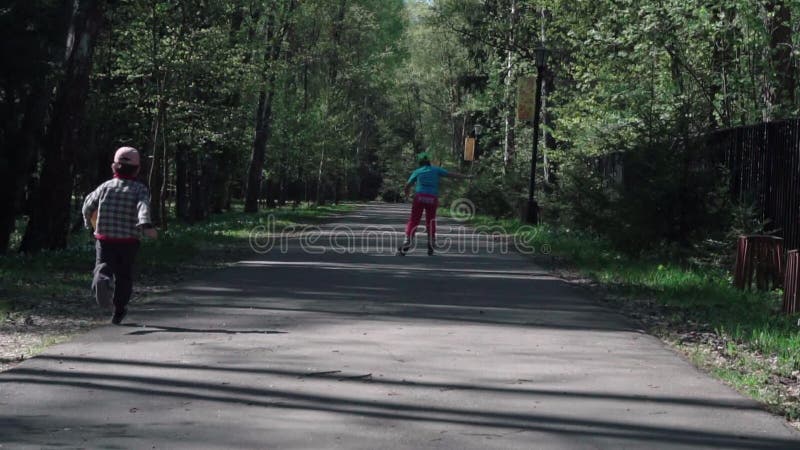 Lite fångar pojken flickan som rider på rullskridskor Långsam-Mo