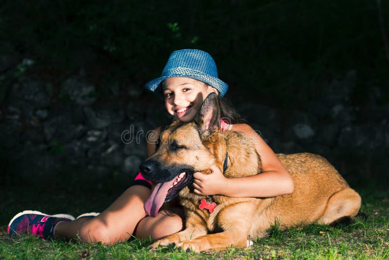 Lite kramar flickan hennes hund för den tyska herden arkivbilder Lite kramar flickan hennes hund för den tyska herden arkivbilder