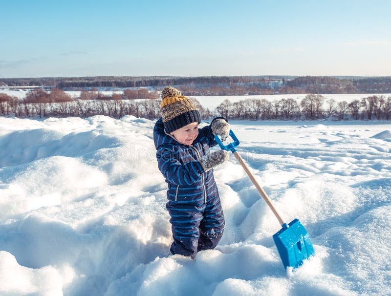 Lite parkerar pojken av 3 gamla år, in i vintern, lekar med en skyffel, gräver snö Lycklig gladlynt ljus solig dag royaltyfria bilder Lite parkerar pojken av 3 gamla år, in i vintern, lekar med en skyffel, gräver snö Lycklig gladlynt ljus solig dag royaltyfria bilder
