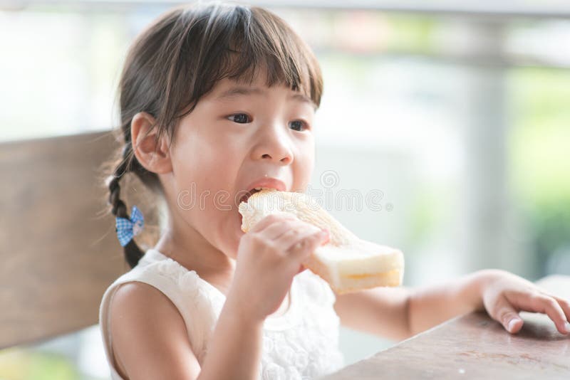 Asian child eating butter toast at cafe. Outdoor family lifestyle with natural light. Asian child eating butter toast at cafe. Outdoor family lifestyle with natural light.