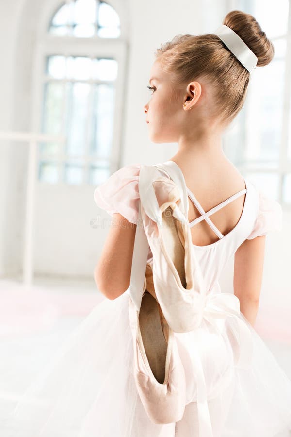 Liten ballerinaflicka i en ballerinakjol Förtjusande barn som dansar klassisk balett i en vit studio