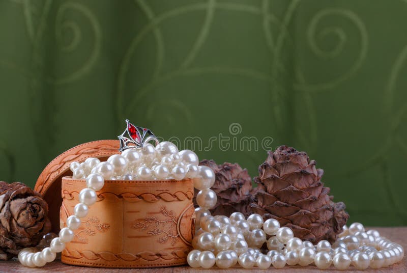 Small birch bark casket with pearl beads and cedar cones on green fabric background. Small birch bark casket with pearl beads and cedar cones on green fabric background
