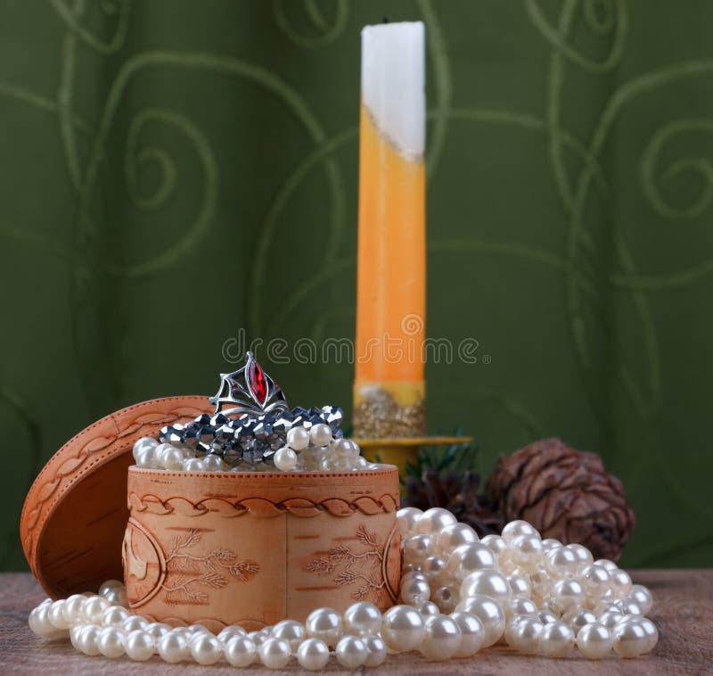 Small birch bark casket with jewelry surrounded by pearls on unfocused background of candle and cones. Small birch bark casket with jewelry surrounded by pearls on unfocused background of candle and cones
