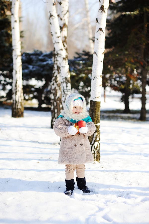 Liten flicka i ett pälslag och fluffiga Orenburg sjalar med en app royaltyfri bild Liten flicka i ett pälslag och fluffiga Orenburg sjalar med en app royaltyfri bild