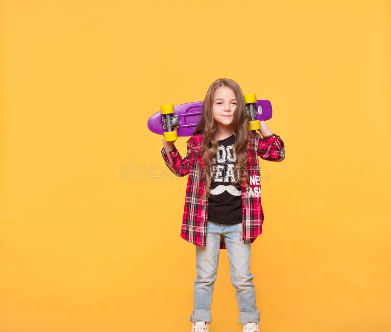 Liten flicka i tillfällig hipsterkläder som isoleras över gul bakgrund arkivbilder Liten flicka i tillfällig hipsterkläder som isoleras över gul bakgrund arkivbilder