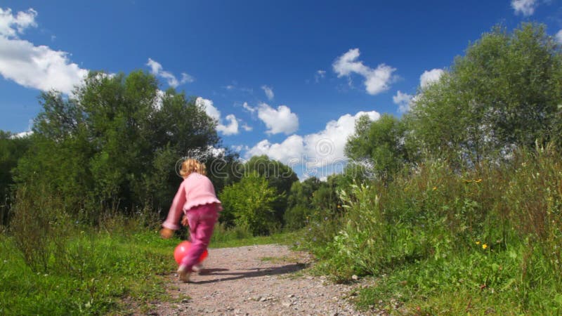 Liten flicka leker med rödballong i parken arkivfilmer