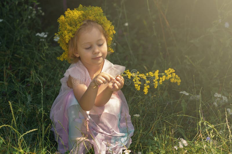 Liten flicka med kronan av blommor som spelar i skogsommartiden royaltyfri fotografi Liten flicka med kronan av blommor som spelar i skogsommartiden royaltyfri fotografi