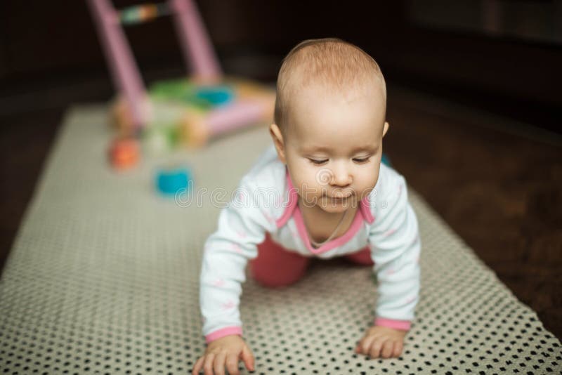 Liten flicka som hemma kryper på golvet på mattan arkivfoton Liten flicka som hemma kryper på golvet på mattan arkivfoton
