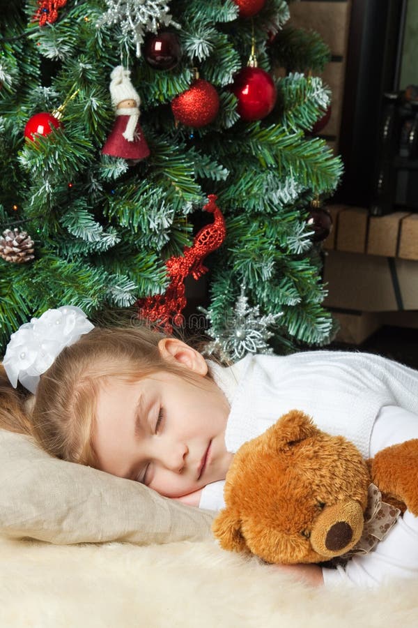 Liten flicka som sovar nära jultree arkivbilder Liten flicka som sovar nära jultree arkivbilder