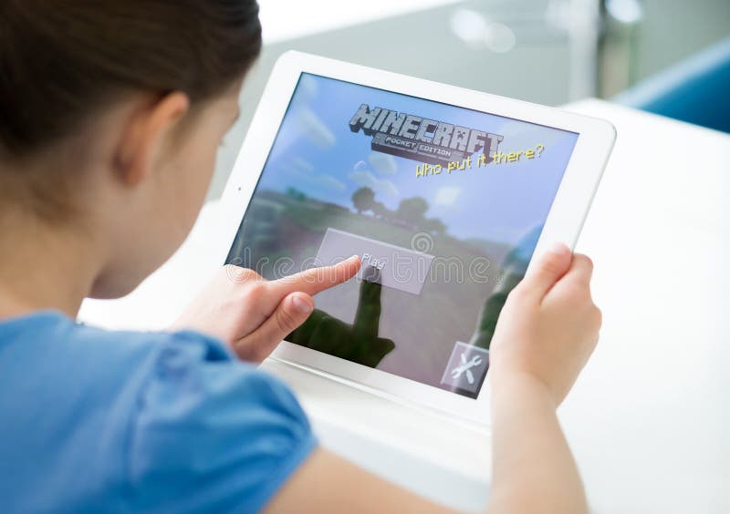 KIEV, UKRAINE - MAY 21, 2014: Little girl start playing Minecraft game on brand new Apple iPad Air. Minecraft is very popular game for mobile devices, was released for iOS version on November 17, 2011. KIEV, UKRAINE - MAY 21, 2014: Little girl start playing Minecraft game on brand new Apple iPad Air. Minecraft is very popular game for mobile devices, was released for iOS version on November 17, 2011