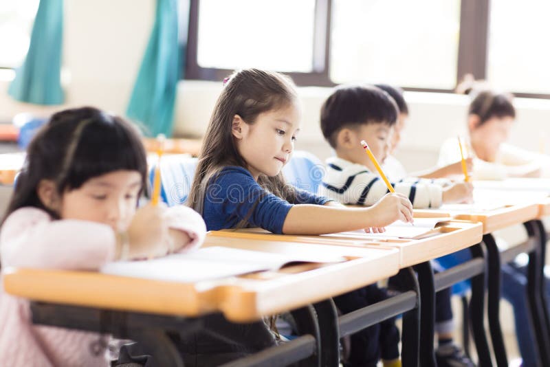 Liten flicka som studerar i klassrumet arkivbild Liten flicka som studerar i klassrumet arkivbild