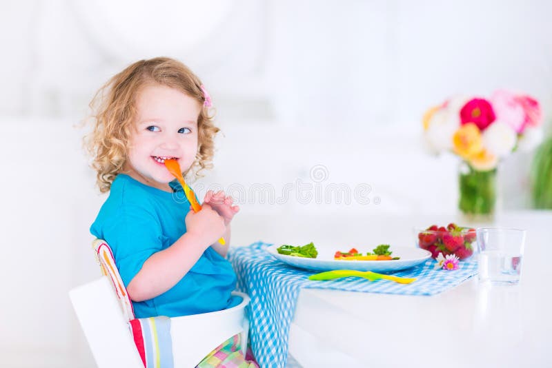 Liten flicka som äter sallad för lunch arkivbild Liten flicka som äter sallad för lunch arkivbild