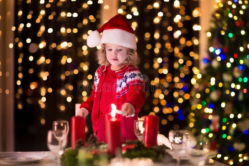 Liten flickabelysningstearinljus på julmatställen royaltyfri fotografi Liten flickabelysningstearinljus på julmatställen royaltyfri fotografi