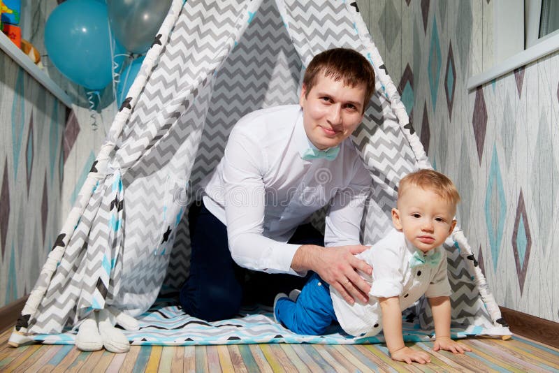 Small male child with fater on the floor in wigwam or teepee during a photo shoot in the room in 1 year. Small male child with fater on the floor in wigwam or teepee during a photo shoot in the room in 1 year