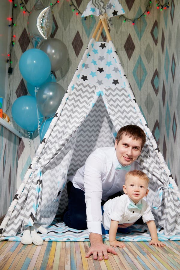 Small male child with fater on the floor in wigwam or teepee during a photo shoot in the room in 1 year. Small male child with fater on the floor in wigwam or teepee during a photo shoot in the room in 1 year